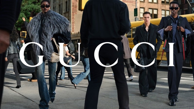 Sheila Bawar, Henry Mouw and Adamu Bulus wear GucciCore tailoring and denim beside a yellow school bus. Gucci logo across the photograph.