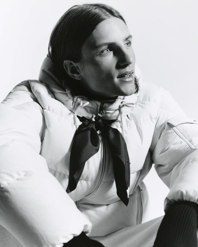 Black-and-white portrait of Indiana van't Slot in a light quilted puffer jacket with a dark neckerchief, looking off to the side