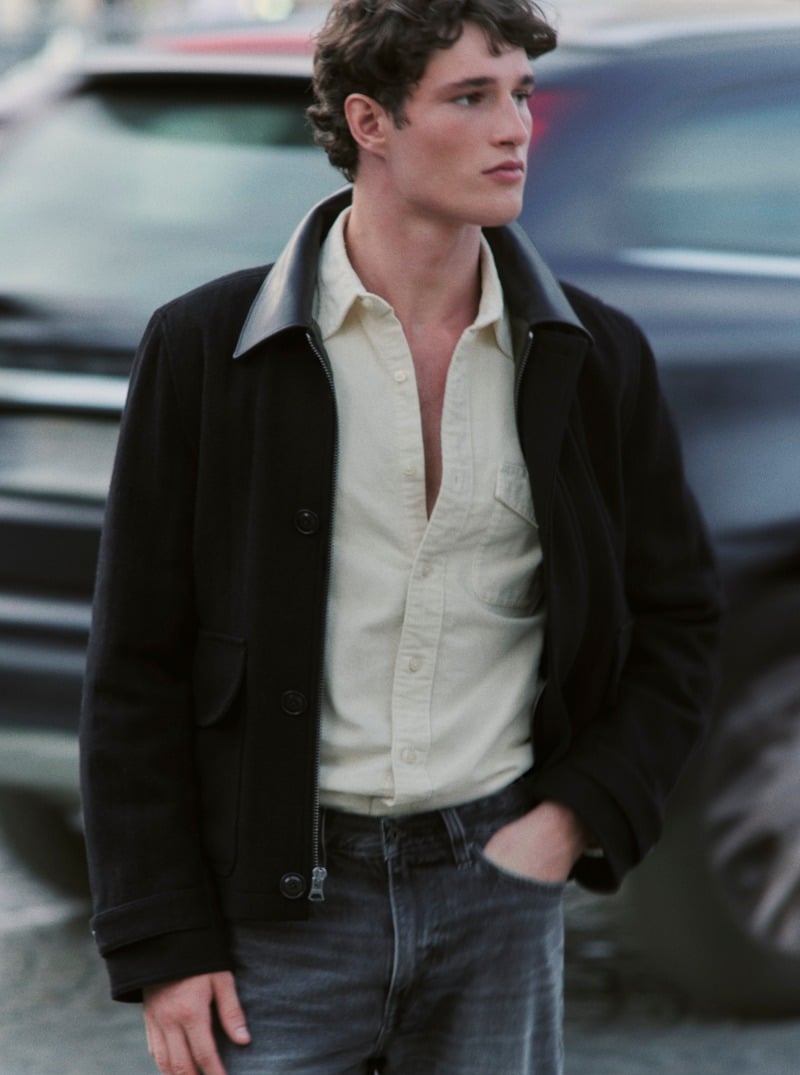Martin Antech wears a black wool barn jacket with a leather collar over a pale shirt and dark jeans.