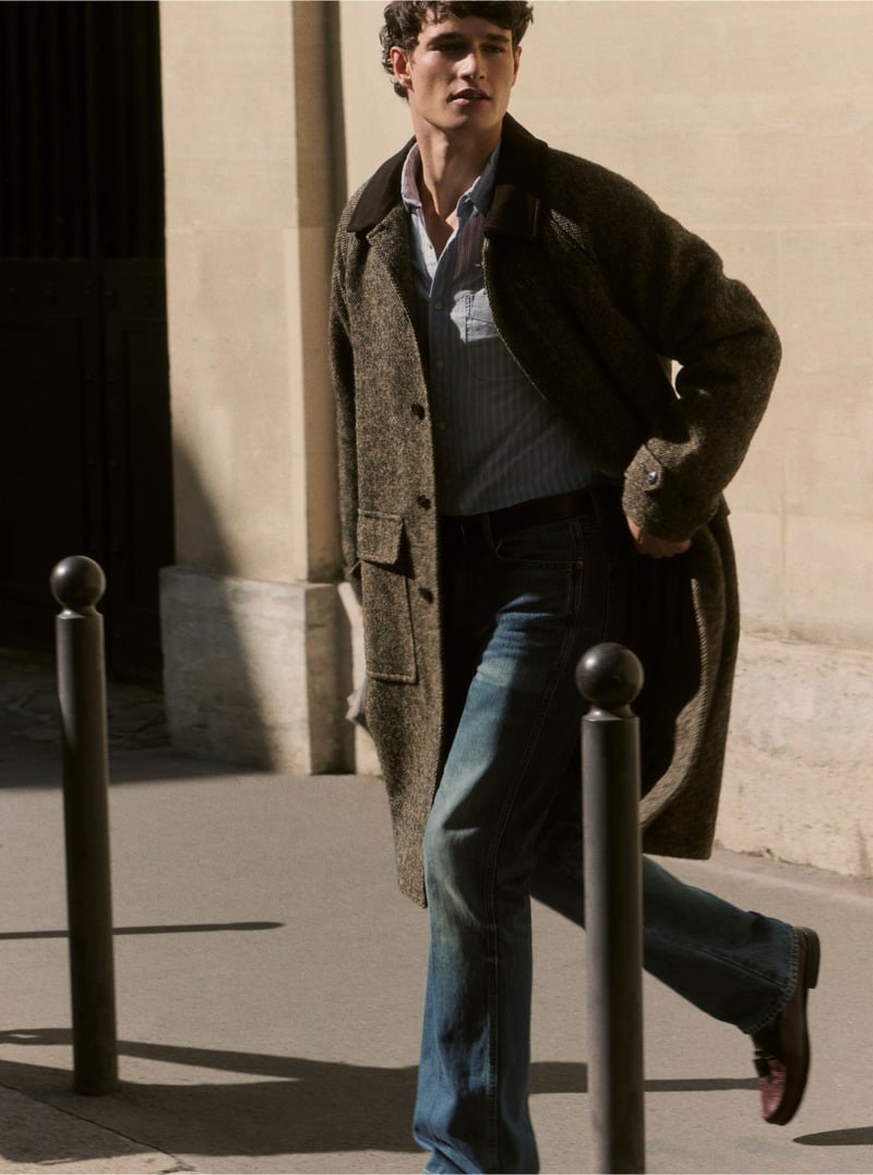 Martin Antech walks along a city street in a Donegal wool car coat, sunglasses, shirt and blue jeans.