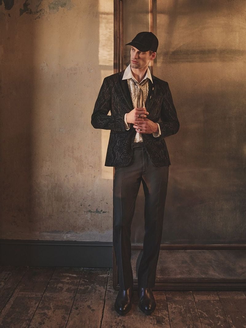 David Trulik wears dark tailoring with an open collar, scarf, and cap for John Varvatos' fall-winter 2026 campaign