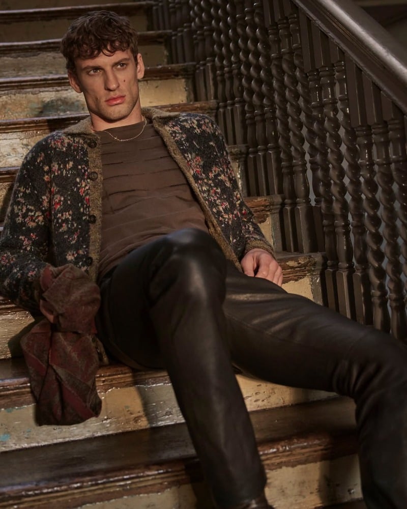 David Trulik reclines on a staircase in the floral Giverny jacquard jacket and leather trousers for John Varvatos' fall-winter 2026 campaign