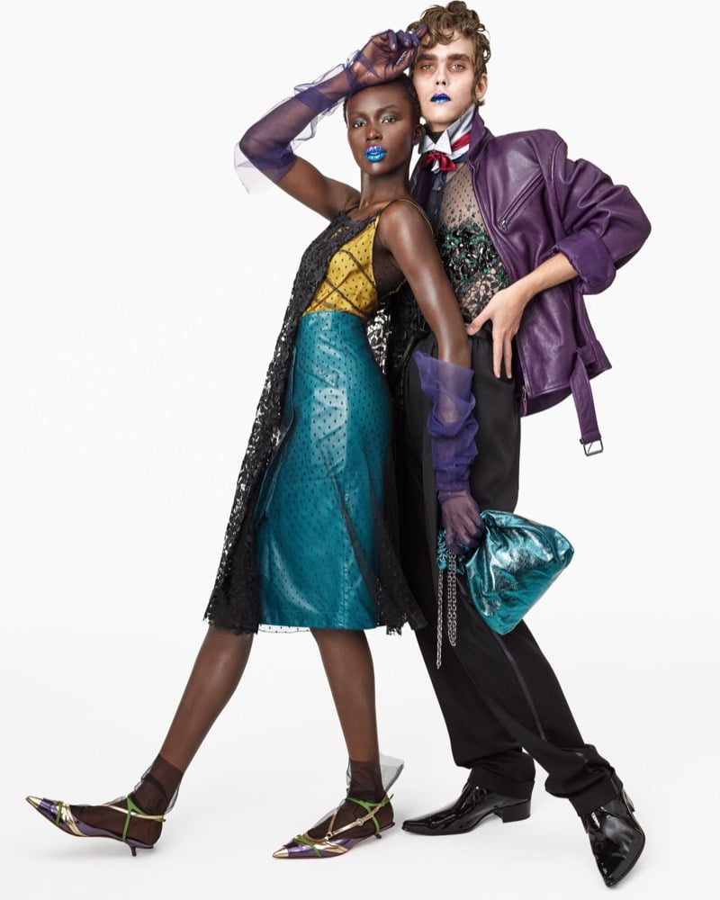 Josephen Akuei in a lace-layered dress with sheer purple gloves and pointed kitten heels beside Frederic Bittner in a purple leather jacket, beaded top, and patent boots