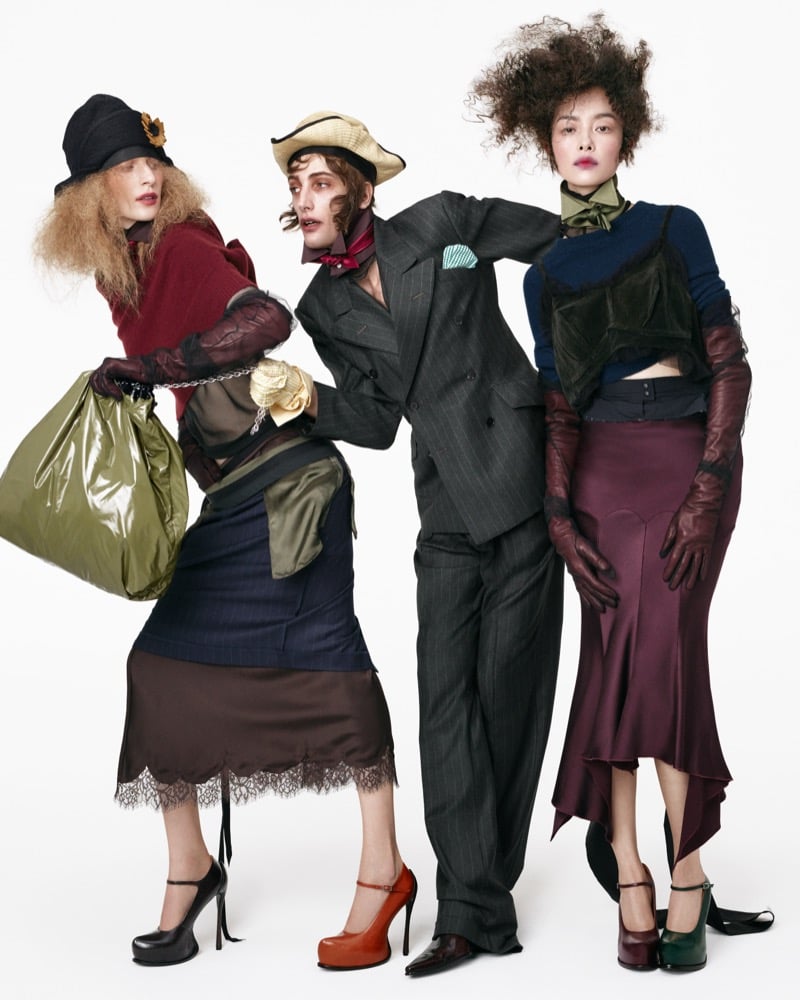 Julia Nobis, Thomas Riguelle, and Anna Bicanova in layered knitwear, a pinstripe double-breasted suit, satin skirts, and long leather gloves