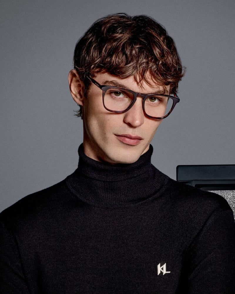 Kit Butler wears brown-framed glasses and a black Karl Lagerfeld turtleneck.