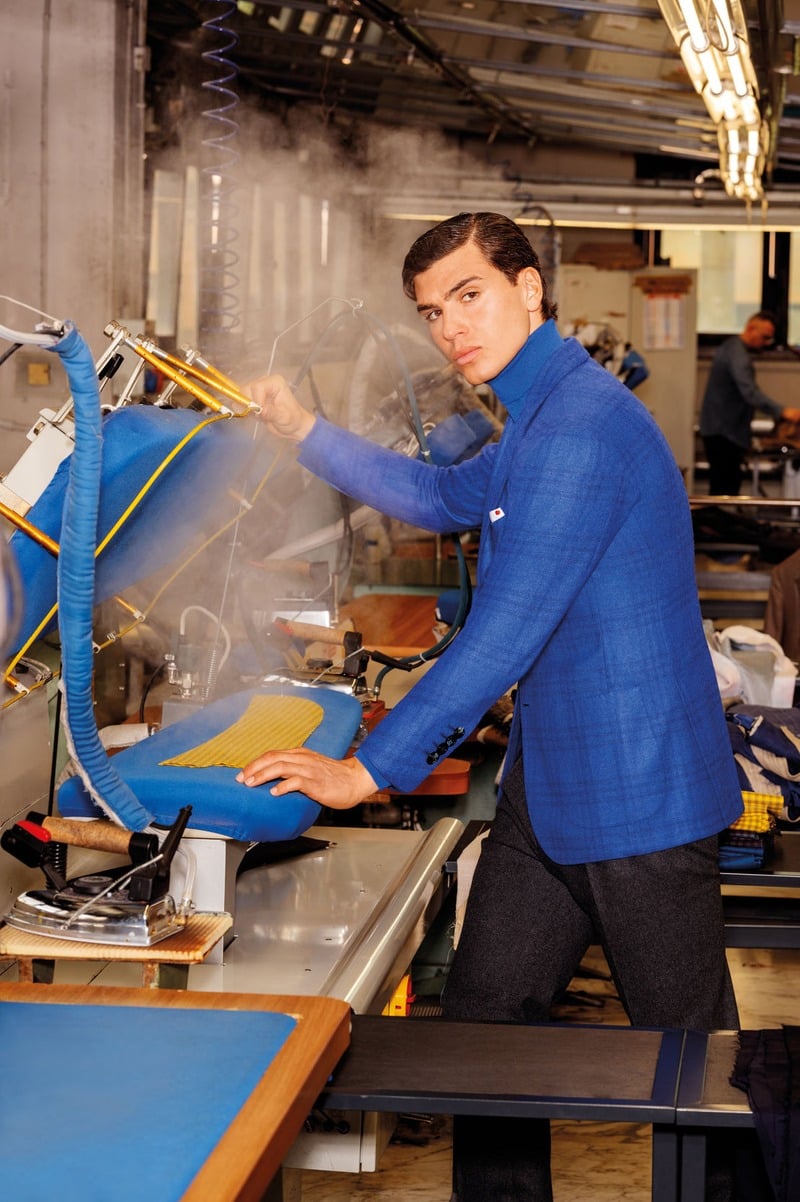 Atila Escolano Sanchez wears a vivid blue Kiton jacket and dark trousers at a steaming pressing station.