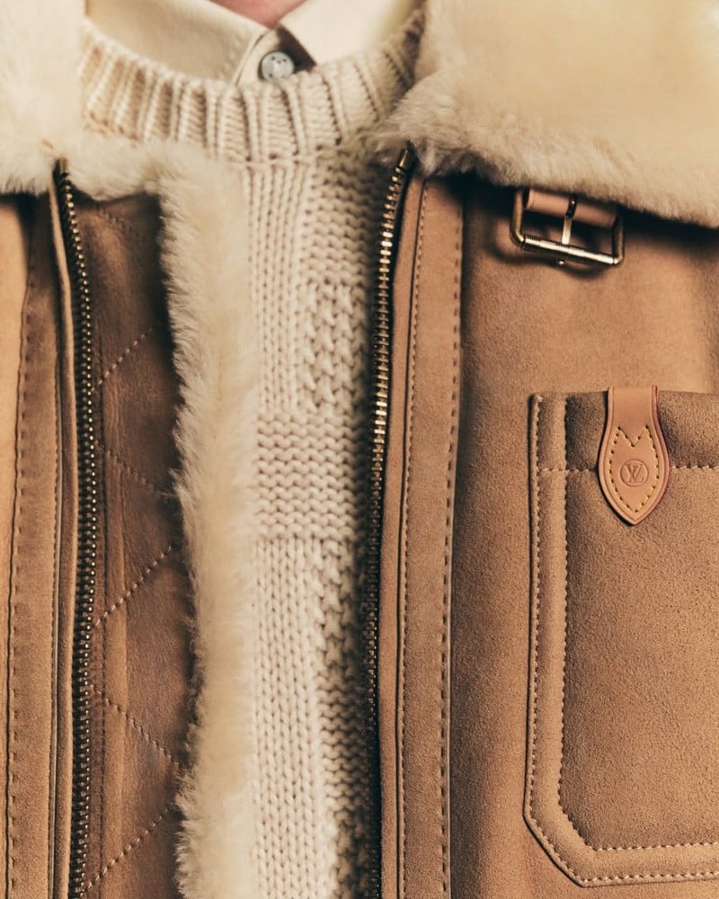 Detail of Callum Turner's jacket and textured knitwear, showing a collar buckle and leather pocket tab in the Louis Vuitton Trunk Edition campaign.
