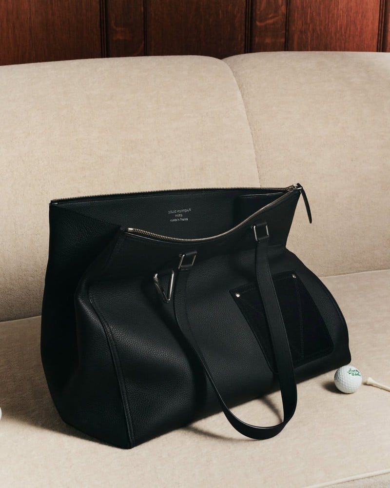 Louis Vuitton leather tote on an upholstered seat beside a golf ball and tee in the Trunk Edition campaign.