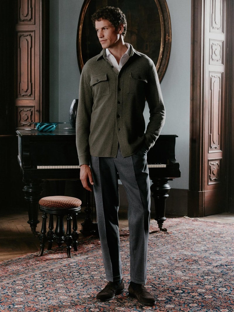 A man wears an olive jacket with dark trousers.