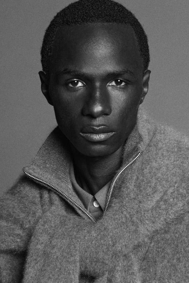 Malick Bodian wears a brushed cashmere zip-up sweater over a collared shirt.