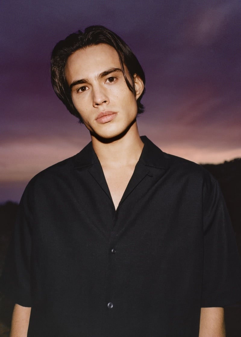 Louis Baines wears a plain black Cuban-collar shirt in Mango’s 2022 edit.