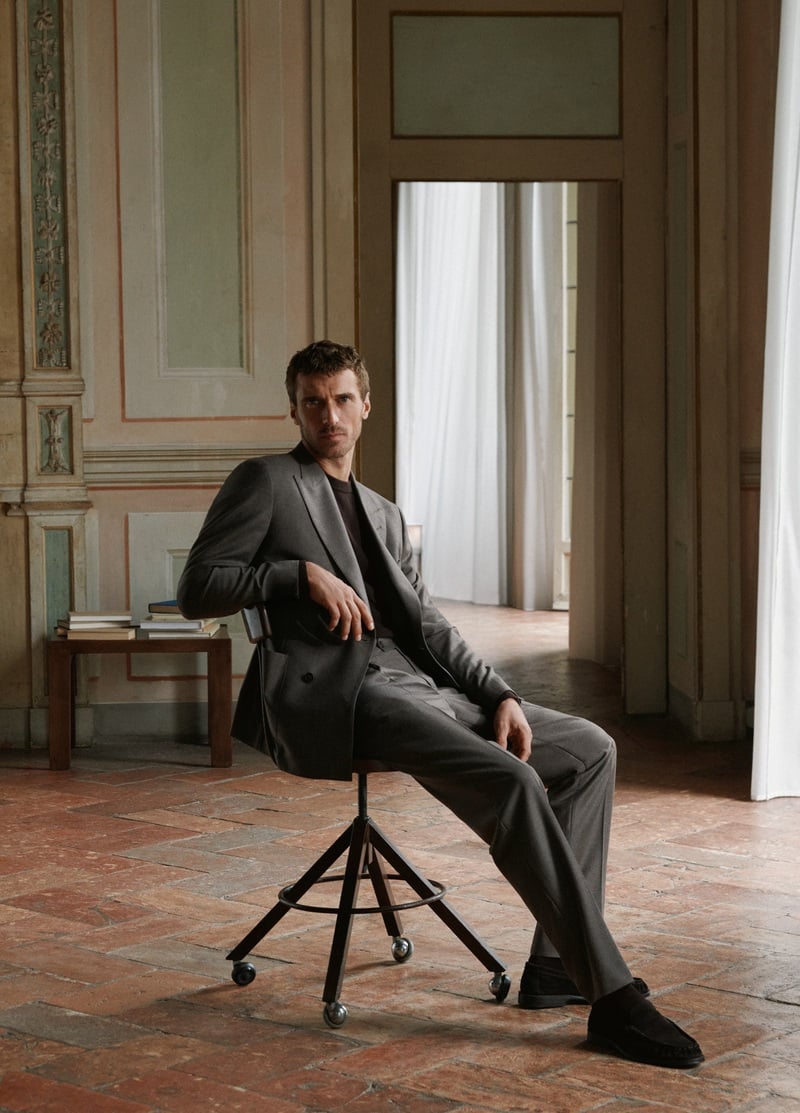 Clément Chabernaud relaxes on a rolling chair in a double-breasted jacket and matching trousers.