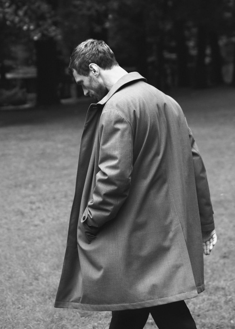 Clément Chabernaud wears a trench coat in a black-and-white outdoor photograph.