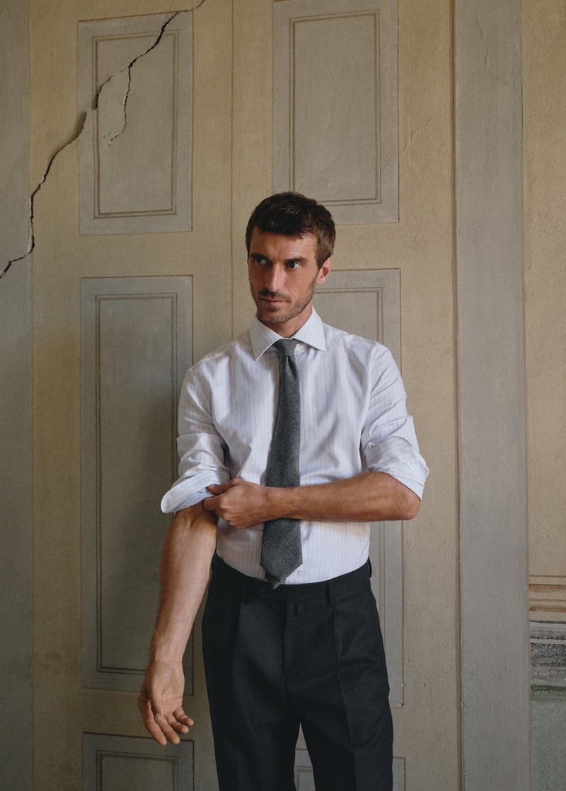 Clément Chabernaud rolls up the sleeves of a striped shirt worn with a tie and dark trousers.