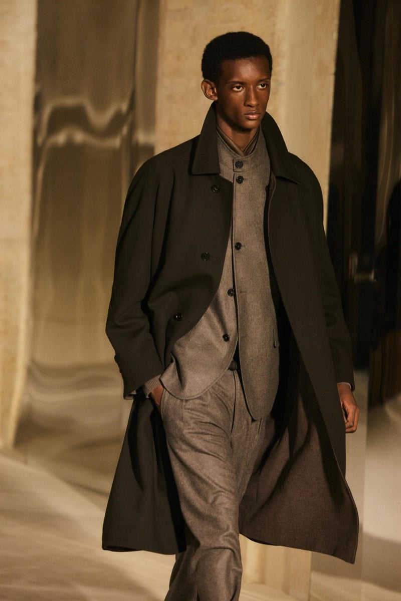 Massimo Dutti Limited Edition fall-winter 2026: Model wears a dark overcoat over a taupe buttoned knit and matching trousers.
