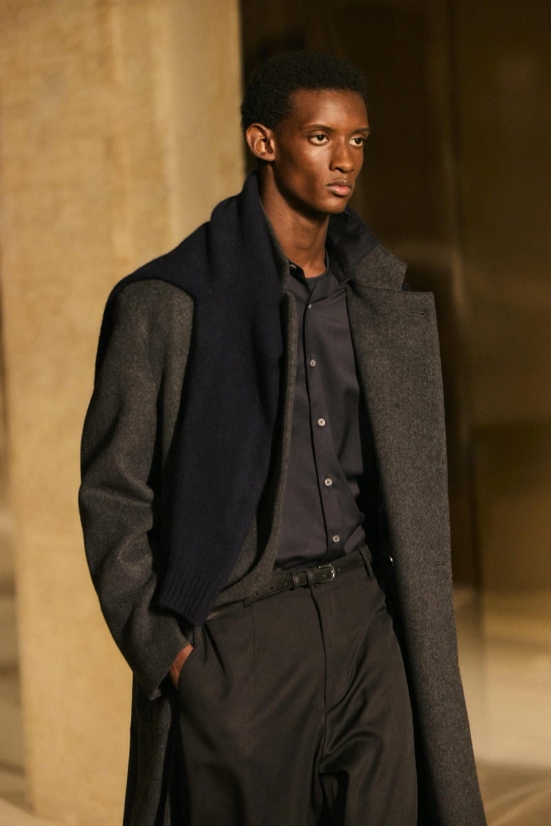 Massimo Dutti Limited Edition fall-winter 2026: Model wears a charcoal overcoat over a dark shirt and trousers with a draped scarf.