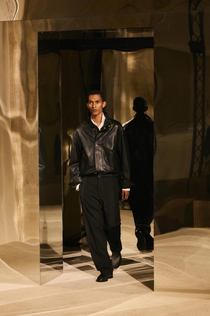 Massimo Dutti Limited Edition fall-winter 2026: Model walks in a black leather blouson, white shirt, and black trousers.
