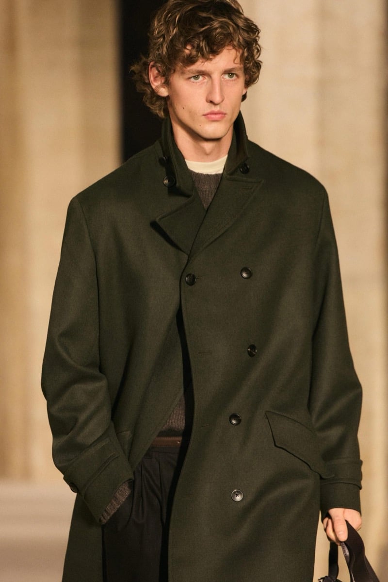 Massimo Dutti Limited Edition fall-winter 2026: Model wears an olive double-breasted overcoat over layered knitwear.