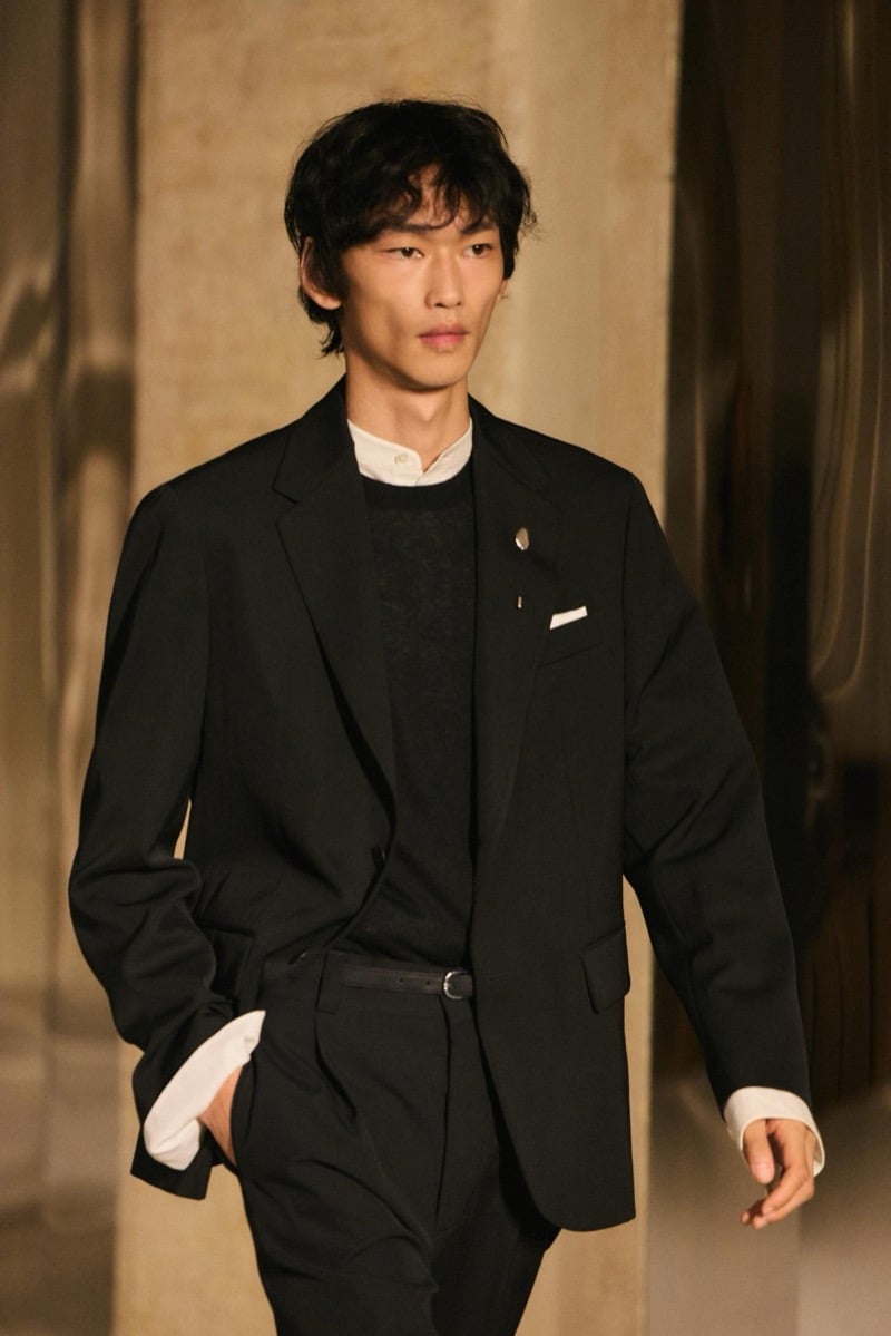 Massimo Dutti Limited Edition fall-winter 2026: Model wears a black blazer over layered black knitwear and a white shirt with pleated trousers.