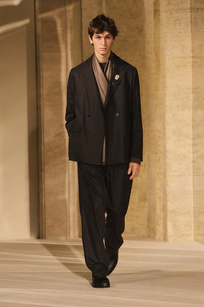 Massimo Dutti Limited Edition fall-winter 2026: Model wears a dark double-breasted blazer with a taupe scarf and wide pleated trousers.