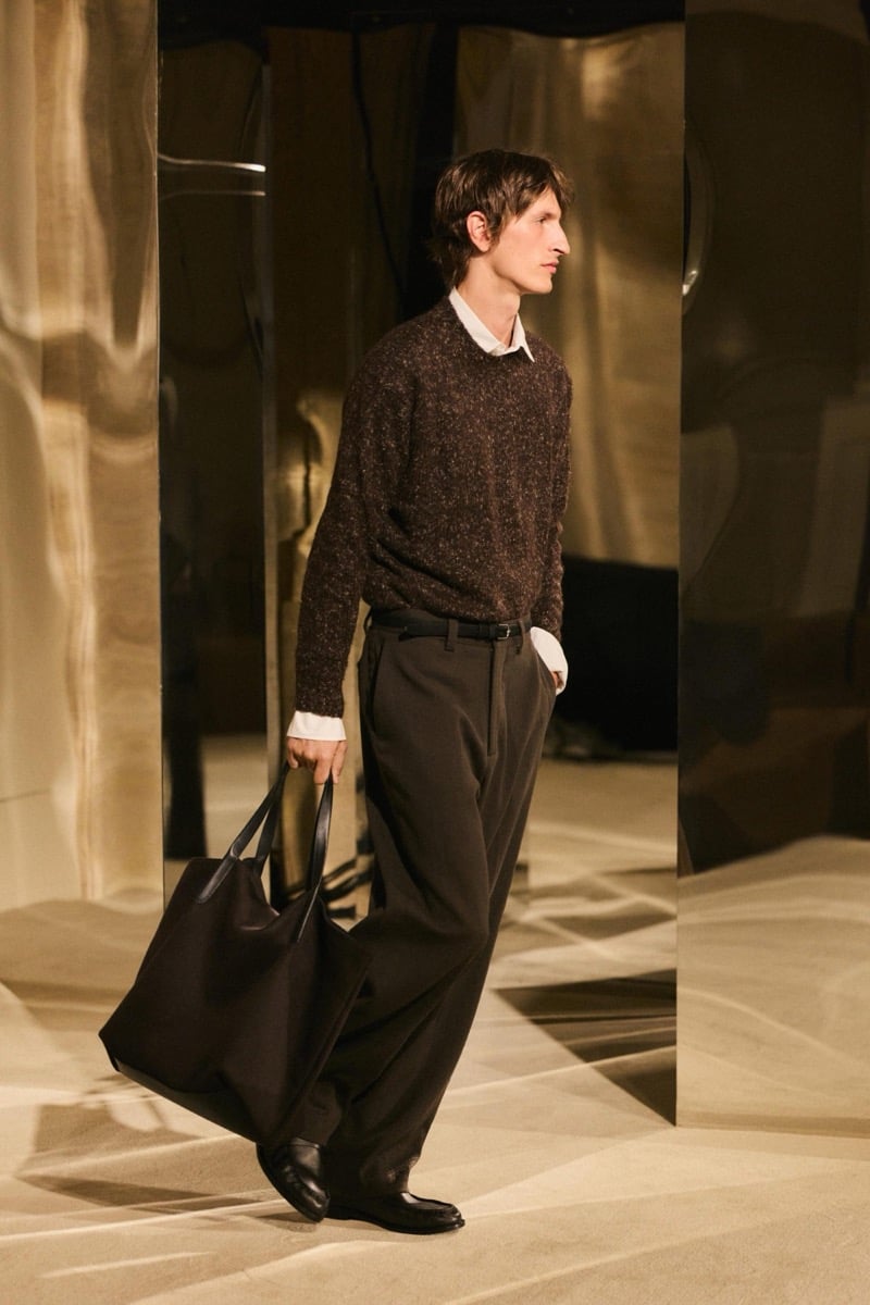 Massimo Dutti Limited Edition fall-winter 2026: Model wears a textured brown sweater, white shirt, and wide brown trousers, carrying a tote.