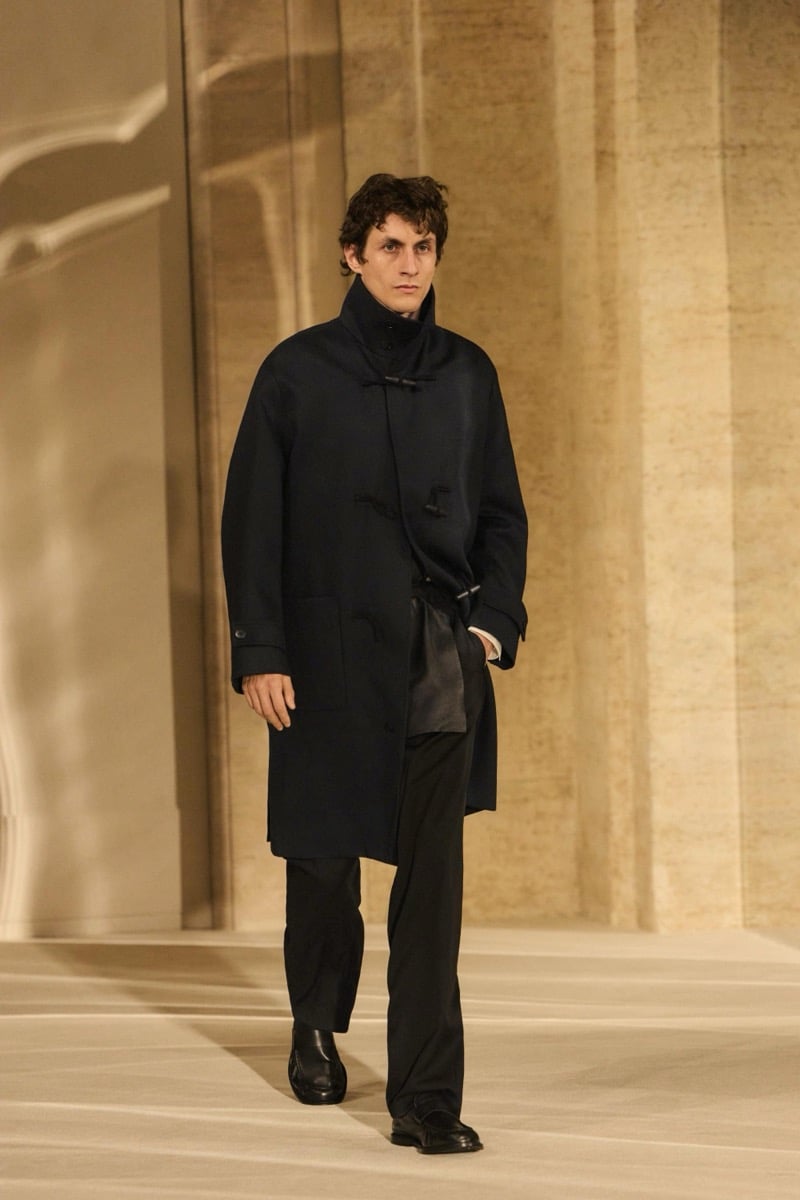 Massimo Dutti Limited Edition fall-winter 2026: Model walks in a black high-collar toggle coat with black trousers.