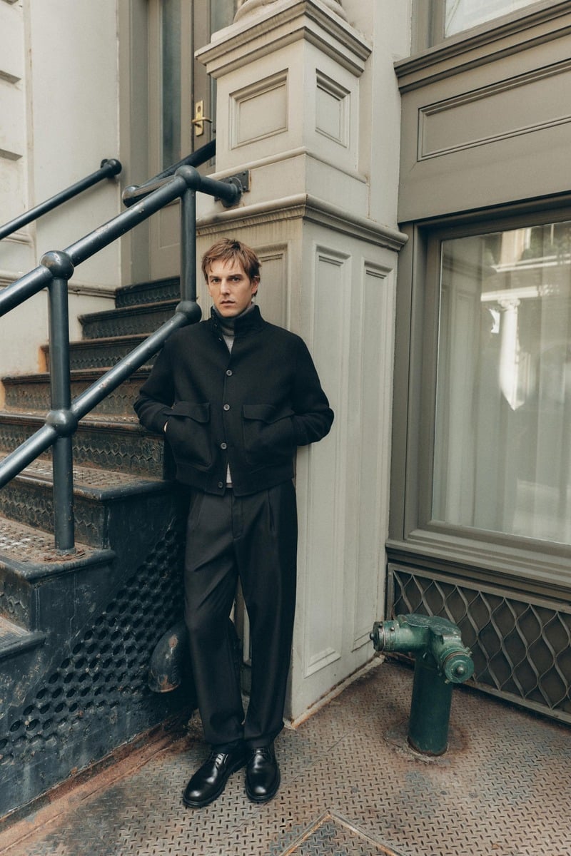 Quentin Demeester stands beside a stoop in a dark buttoned jacket and wide trousers for Massimo Dutti's fall 2026 New York edit.