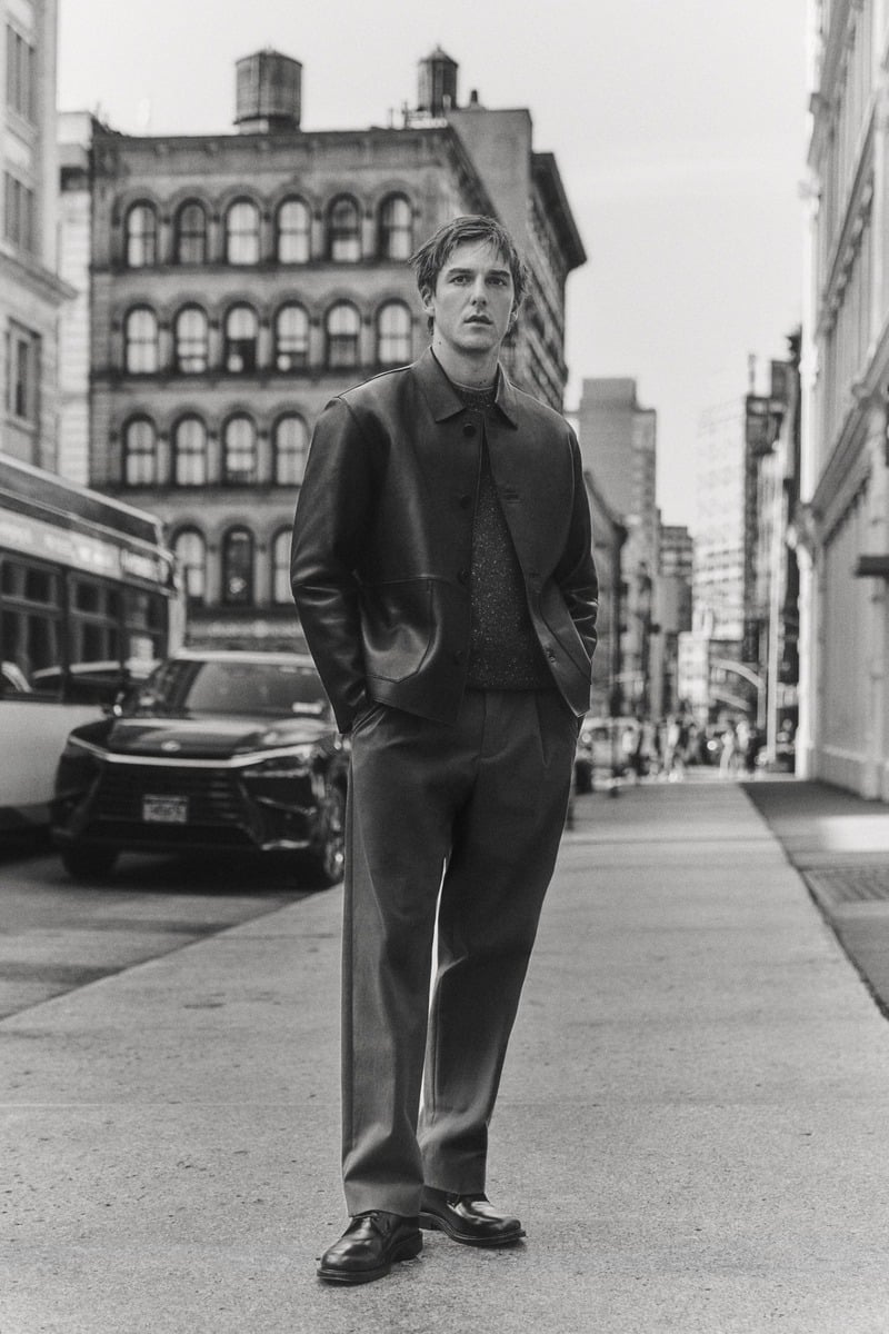 Quentin Demeester walks along a New York street in a collared jacket and pleated trousers in a black-and-white photograph for Massimo Dutti's fall 2026 New York edit.