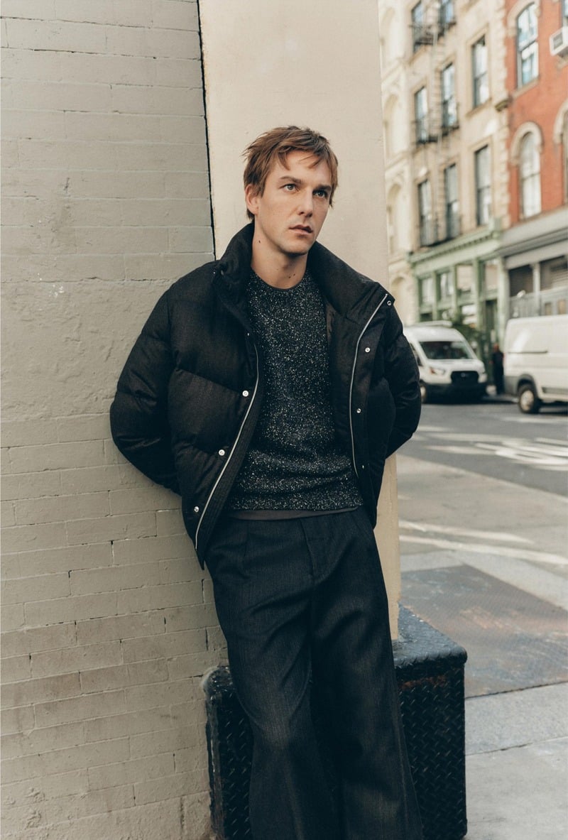 Quentin Demeester wears a padded jacket over a textured sweater beside a New York building for Massimo Dutti's fall 2026 New York edit.