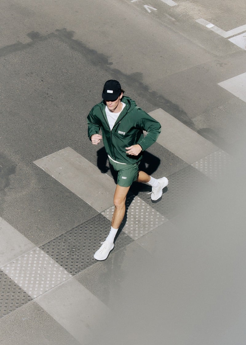 Myles Crosby running in a green jacket and shorts, photographed from above