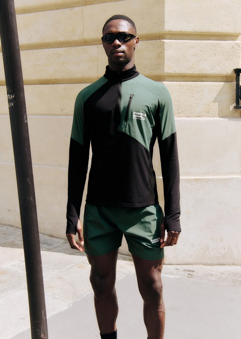 Sadiq Desh wearing a green and black zip-neck layer with green shorts