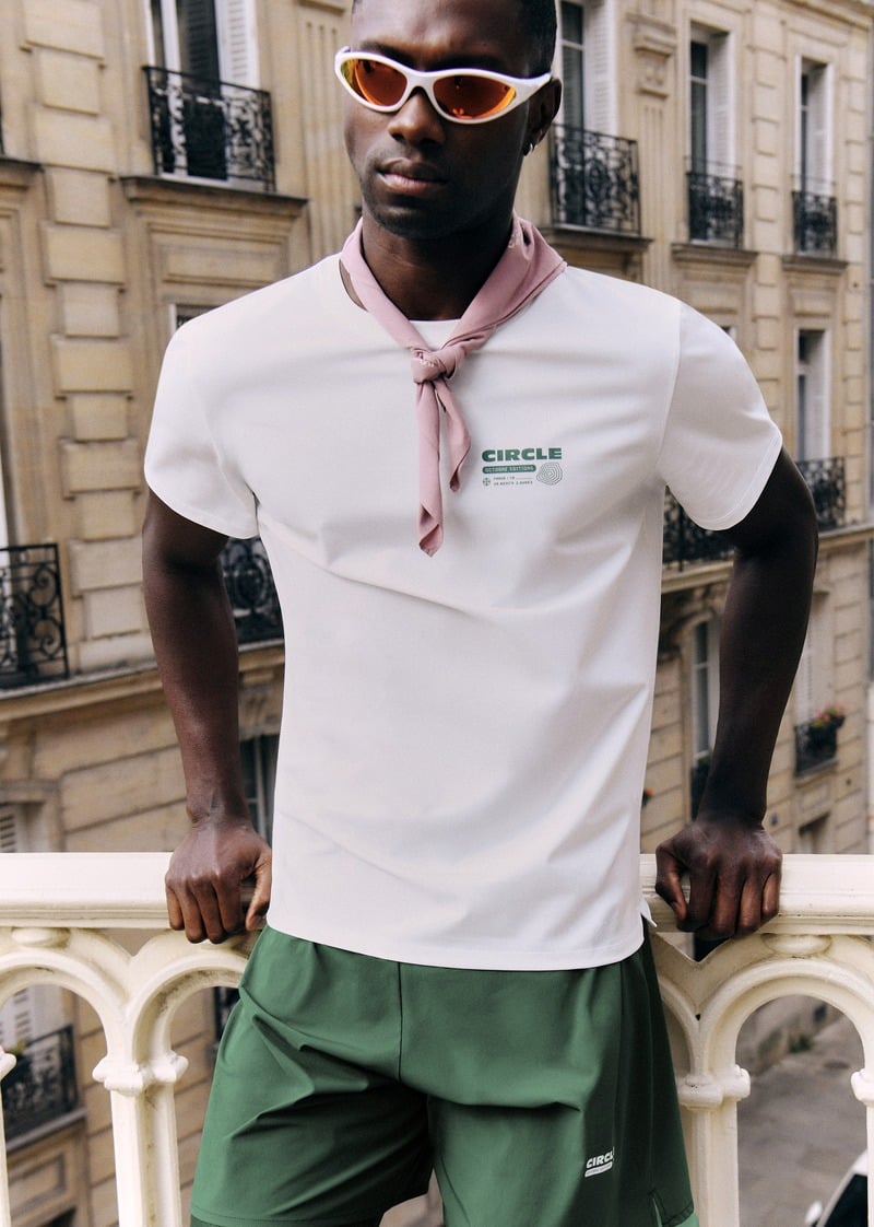 Sadiq Desh wearing a white running T-shirt, green shorts and a neck scarf
