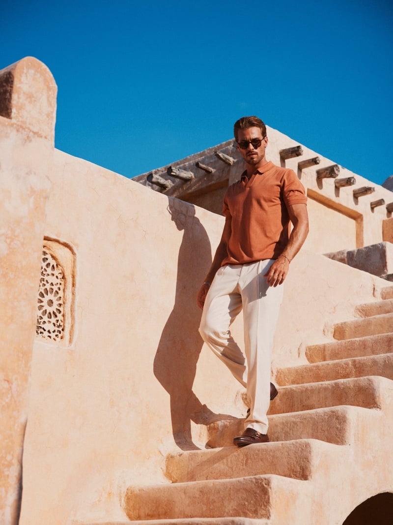 Gonçalo Campos wears a rust shirt, pale trousers and sunglasses on an outdoor staircase.