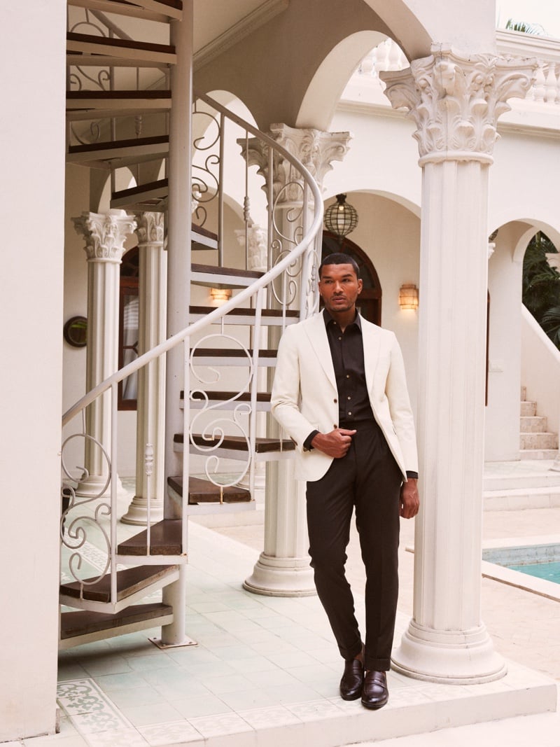 Paulo Lopes Lucio wears a light blazer over a dark shirt and trousers beside a white spiral staircase.