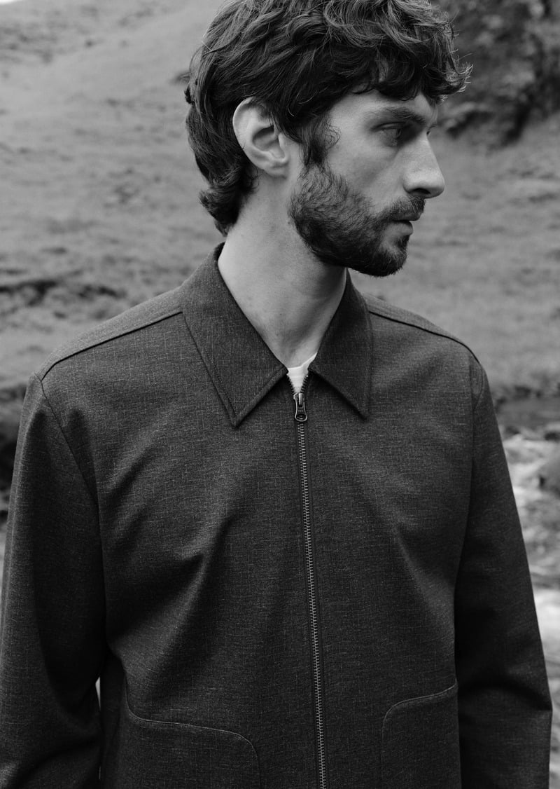 Matthew Bell wears a collared zip-front jacket in a black-and-white portrait.