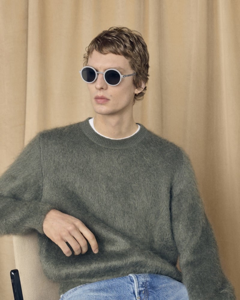 Leon Dame pairs RIMOWA x MYKITA Heritage MR007 round sunglasses with a fuzzy sweater and blue jeans.