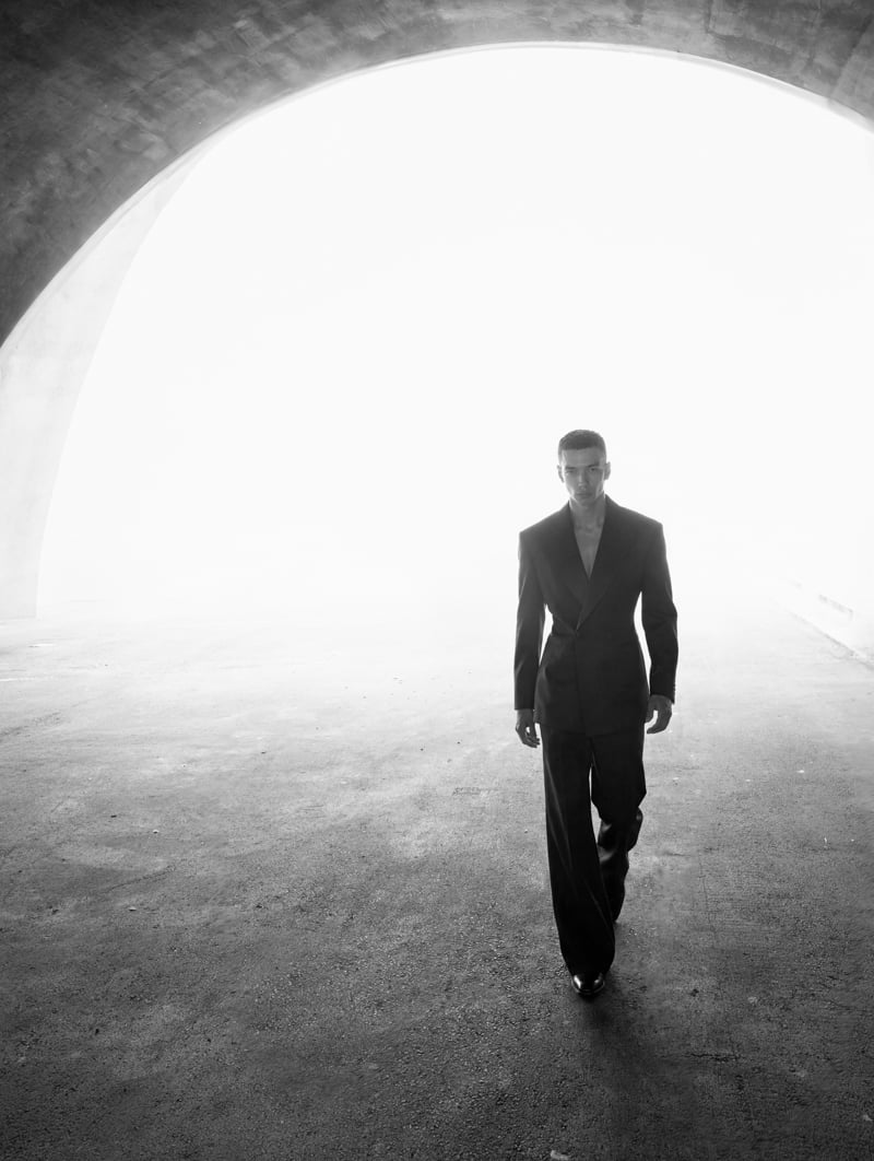 Sasha Profatilov walks through a concrete archway in Saint Laurent by Anthony Vaccarello.
