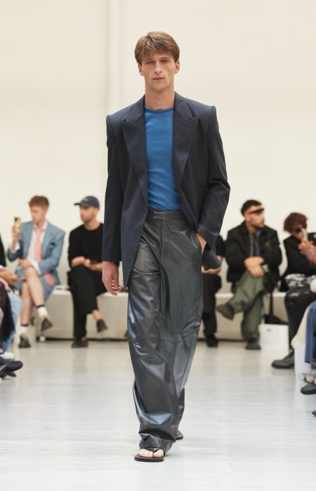 Model wearing a dark tailored jacket, blue top and leather trousers at Situationist spring-summer 2027.