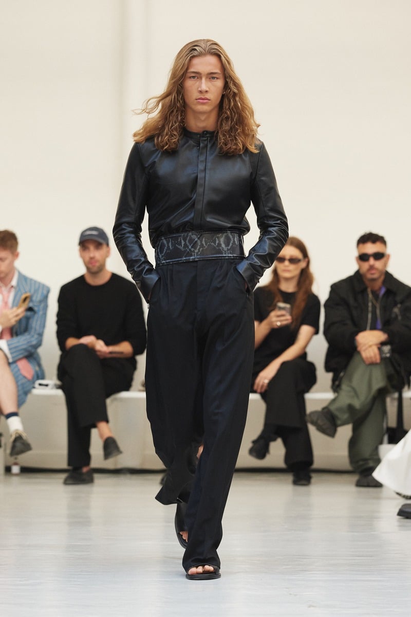 Model wearing a fitted black zip-front jacket and loose trousers at Situationist spring-summer 2027.