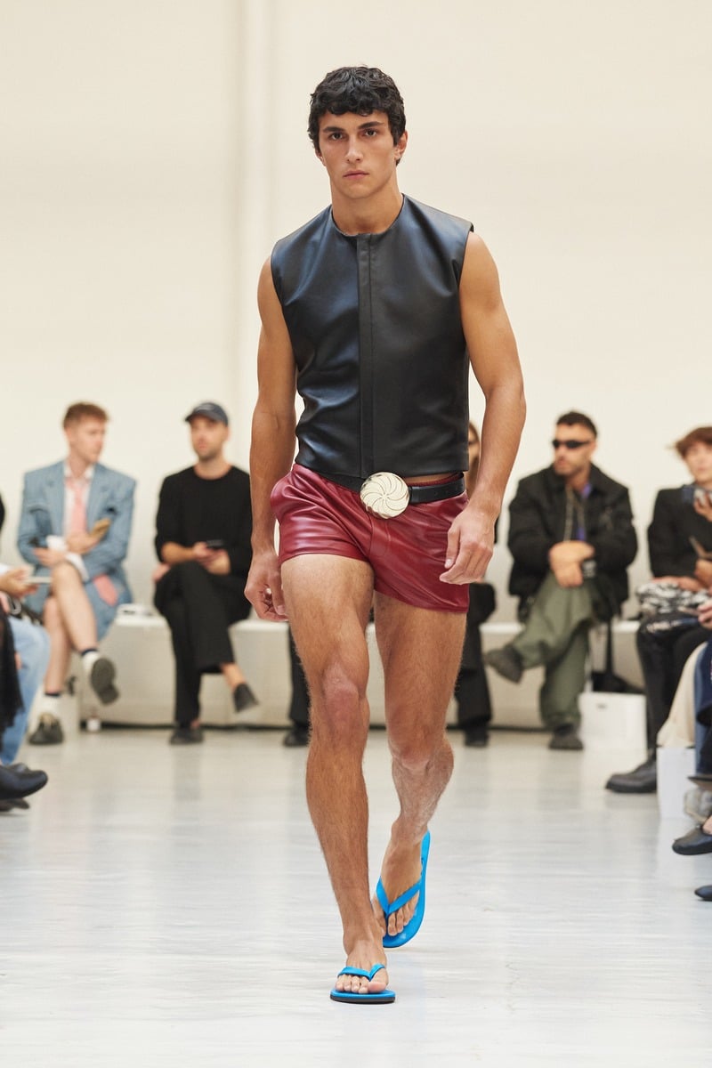 Model wearing a sleeveless leather top, red shorts and a Borjgali belt buckle at Situationist spring-summer 2027.