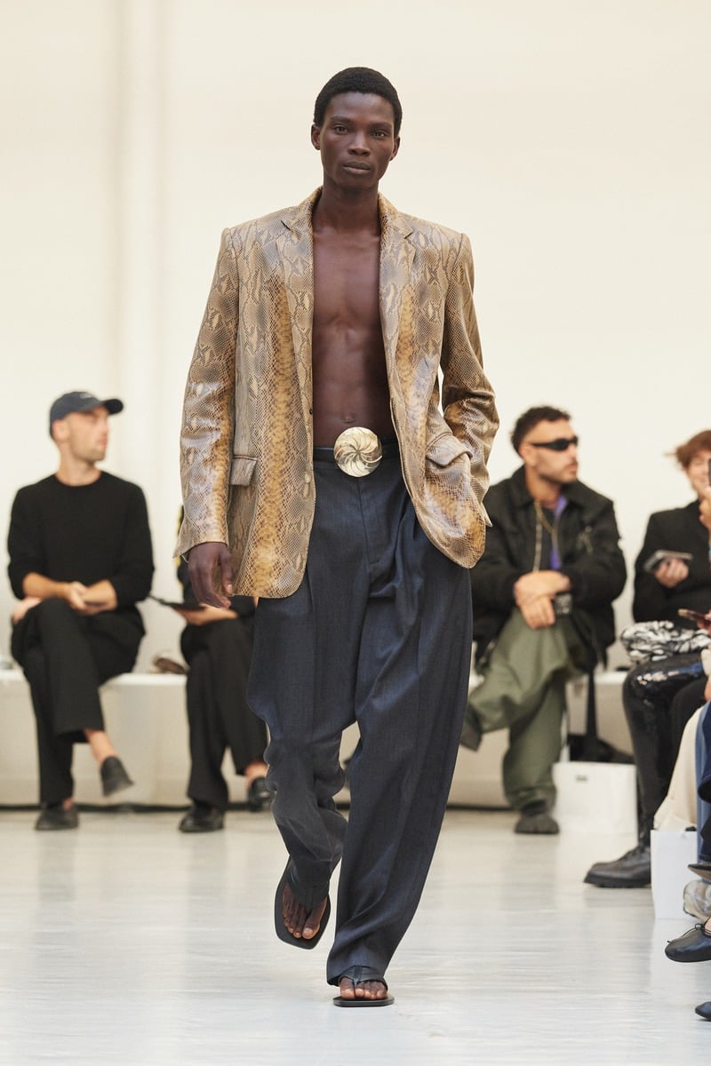 Model wearing a snakeskin-pattern jacket over a bare chest with loose trousers at Situationist spring-summer 2027.