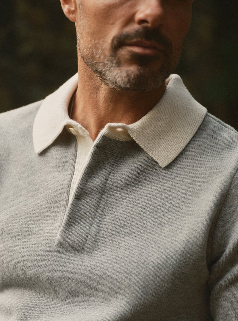 Close-up of a model wearing a gray collared knit rugby sweater. Taylor Stitch winter 2026 collection.