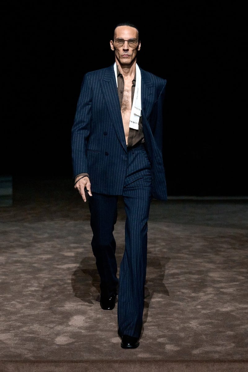 A model wears navy suit with an open pale shirt and sunglasses on the Tom Ford spring-summer 2027 runway.