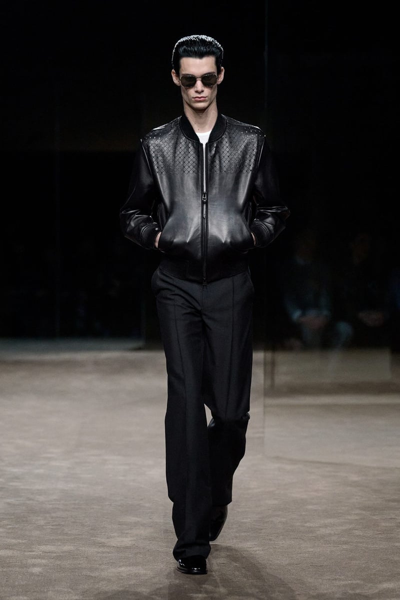 A model wears glossy dark shirt tucked into black trousers on the Tom Ford spring-summer 2027 runway.