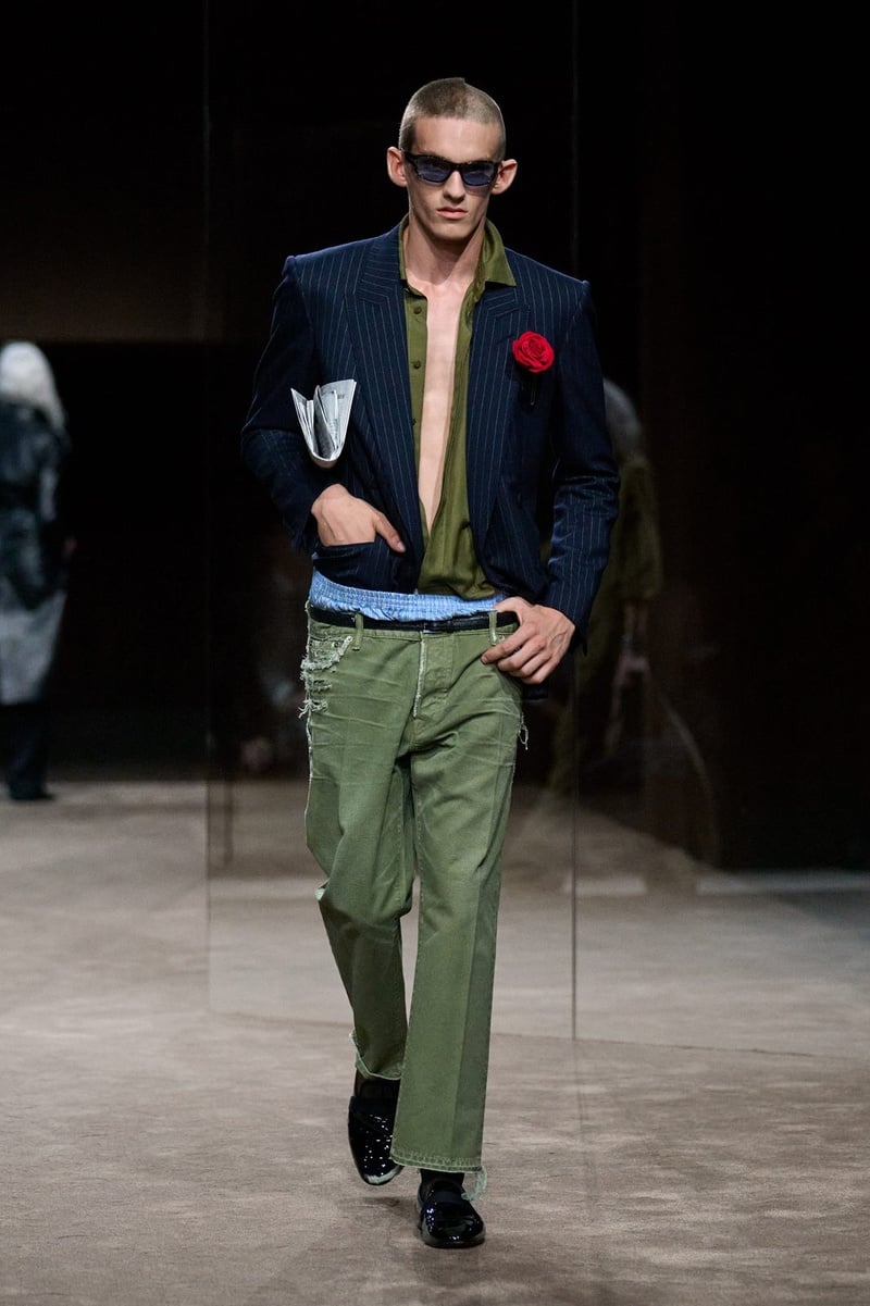 A model wears navy blazer with a red rose, open green shirt, and green trousers on the Tom Ford spring-summer 2027 runway.