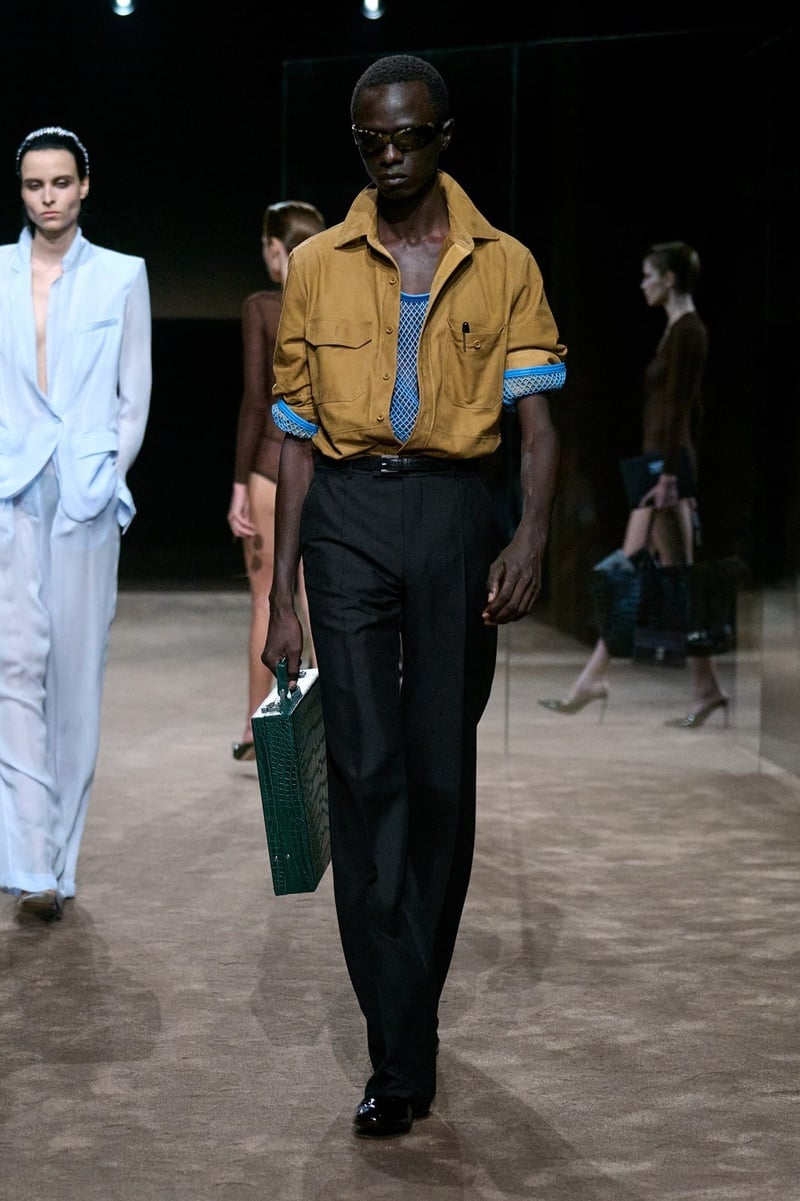 A model wears ochre cropped jacket over an open blue shirt with dark trousers on the Tom Ford spring-summer 2027 runway.