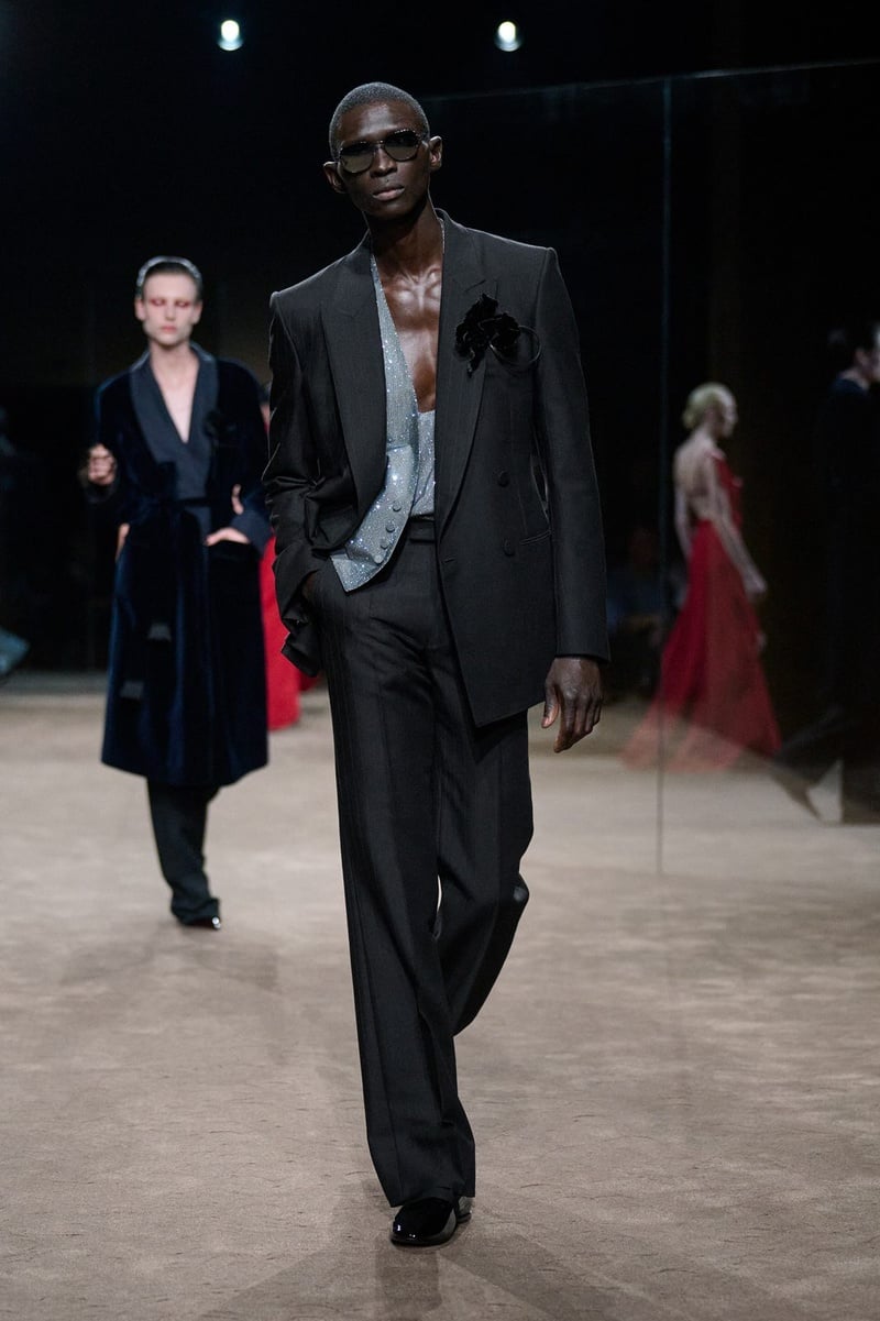 A model wears dark suit over a deeply open shirt on the Tom Ford spring-summer 2027 runway.