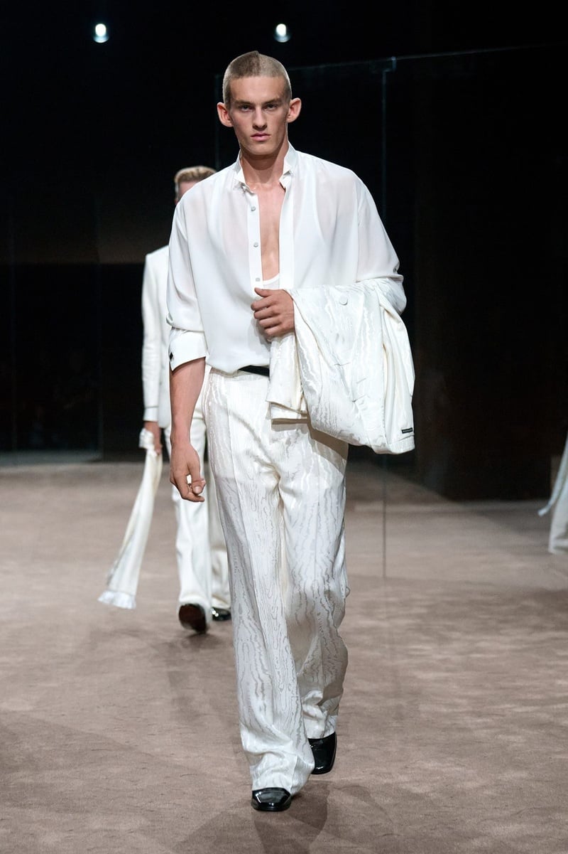 A model wears white jacket and trousers with a draped white scarf on the Tom Ford spring-summer 2027 runway.