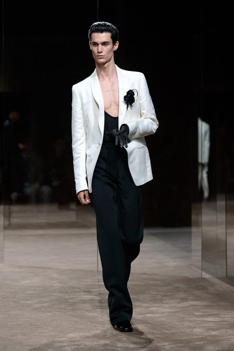 A model wears white jacket over a plunging black top and black trousers on the Tom Ford spring-summer 2027 runway.