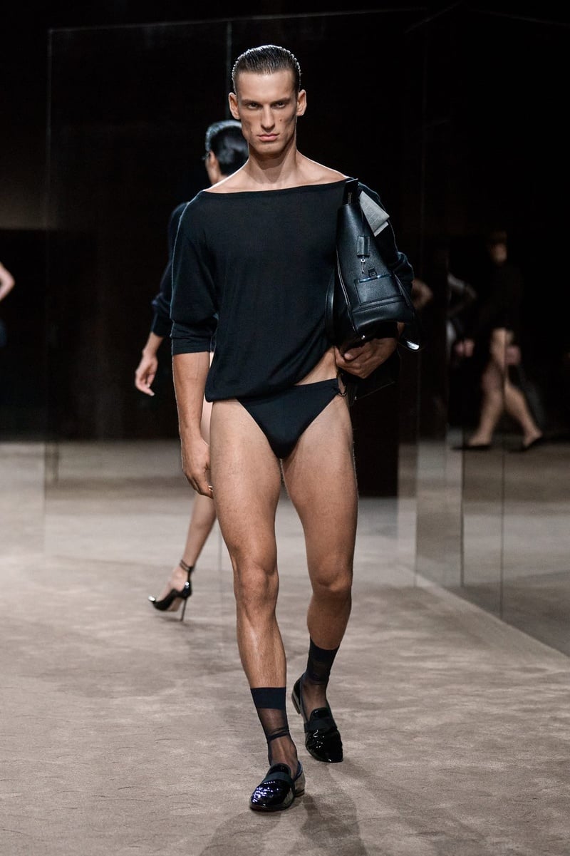 A model wears draped black top and high-cut briefs with a jacket over one shoulder on the Tom Ford spring-summer 2027 runway.